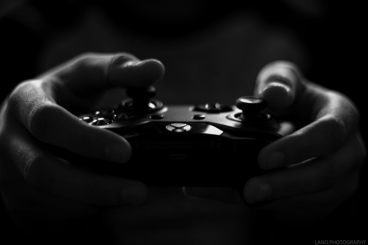 about-img Close-up of hands holding a game controller in a monochrome setting, capturing the essence of gaming.