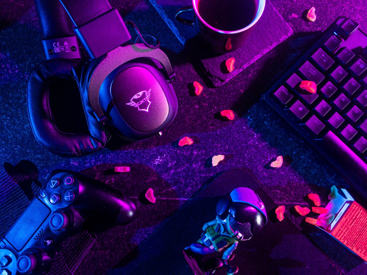 core-values Colorful flat lay of gaming gear including headset, controller, and keyboard under vibrant lighting.